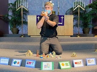 Pastor Scott kneeling with nativity figures