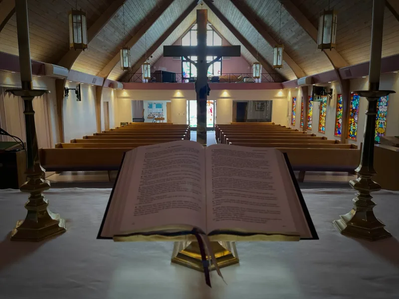 Open Bible on the altar with cross and candlesticks