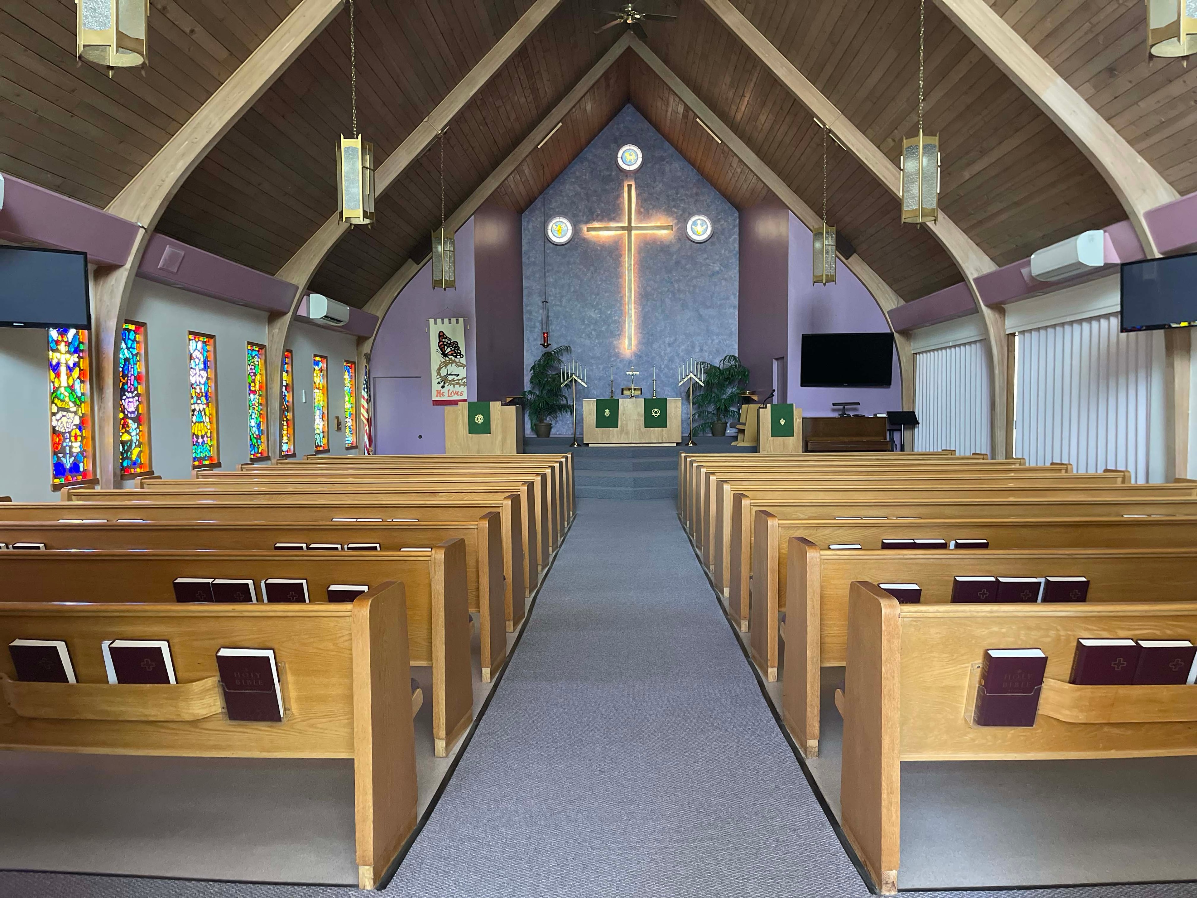 Church sanctuary with wooden pews and neon cross